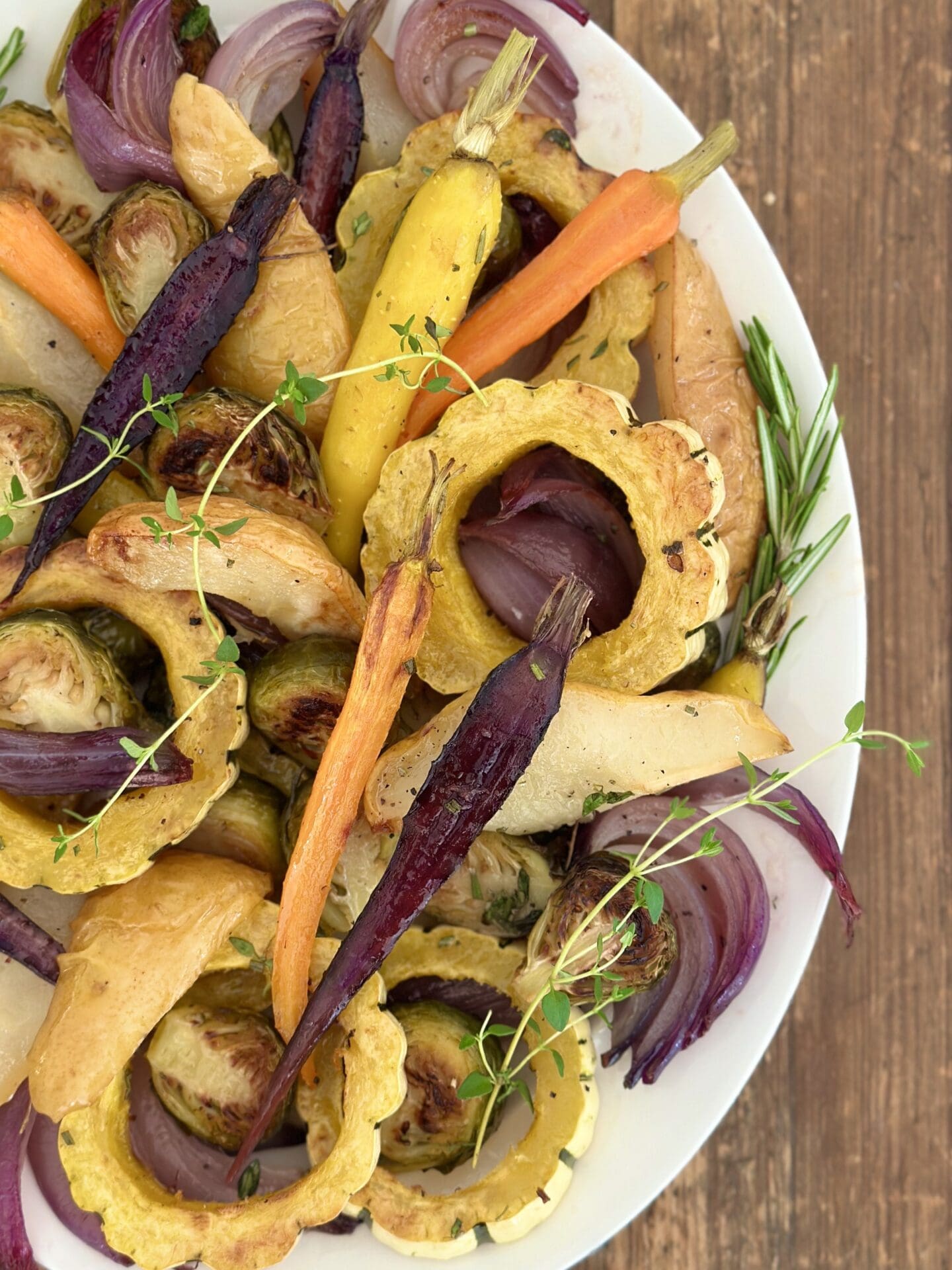 A Thanksgiving side dish of colourful Maple Butter Roasted Vegetables with Pears garnished with fresh herbs