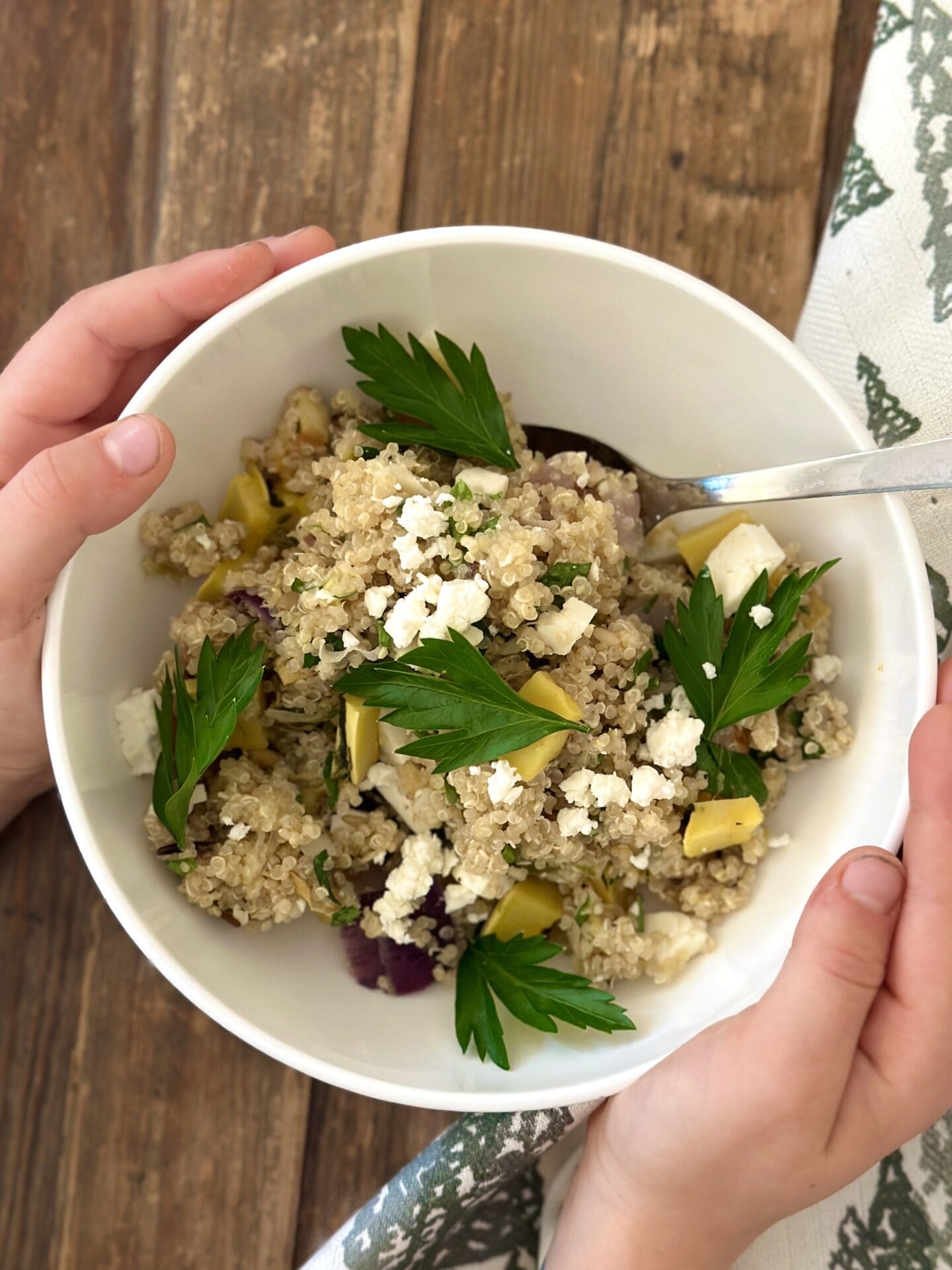 Little hands hold a bowl of Maple Butter Roasted Vegetables and Pear Quinoa salad made from leftover Thanksgiving vegetables