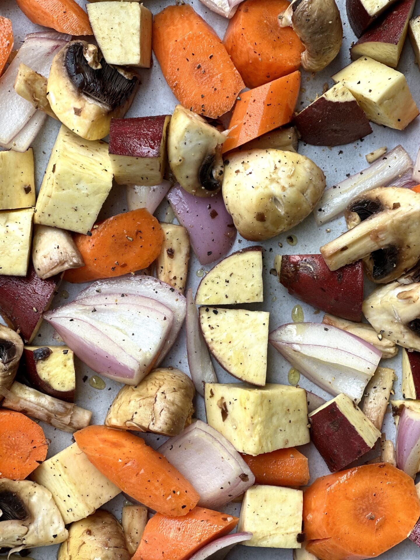 IMG_6966 A medley of diced carrots, Japanese sweet potato, mushrooms and red onion are seen from above, dusted with salt and pepper and ready for roasting in the oven