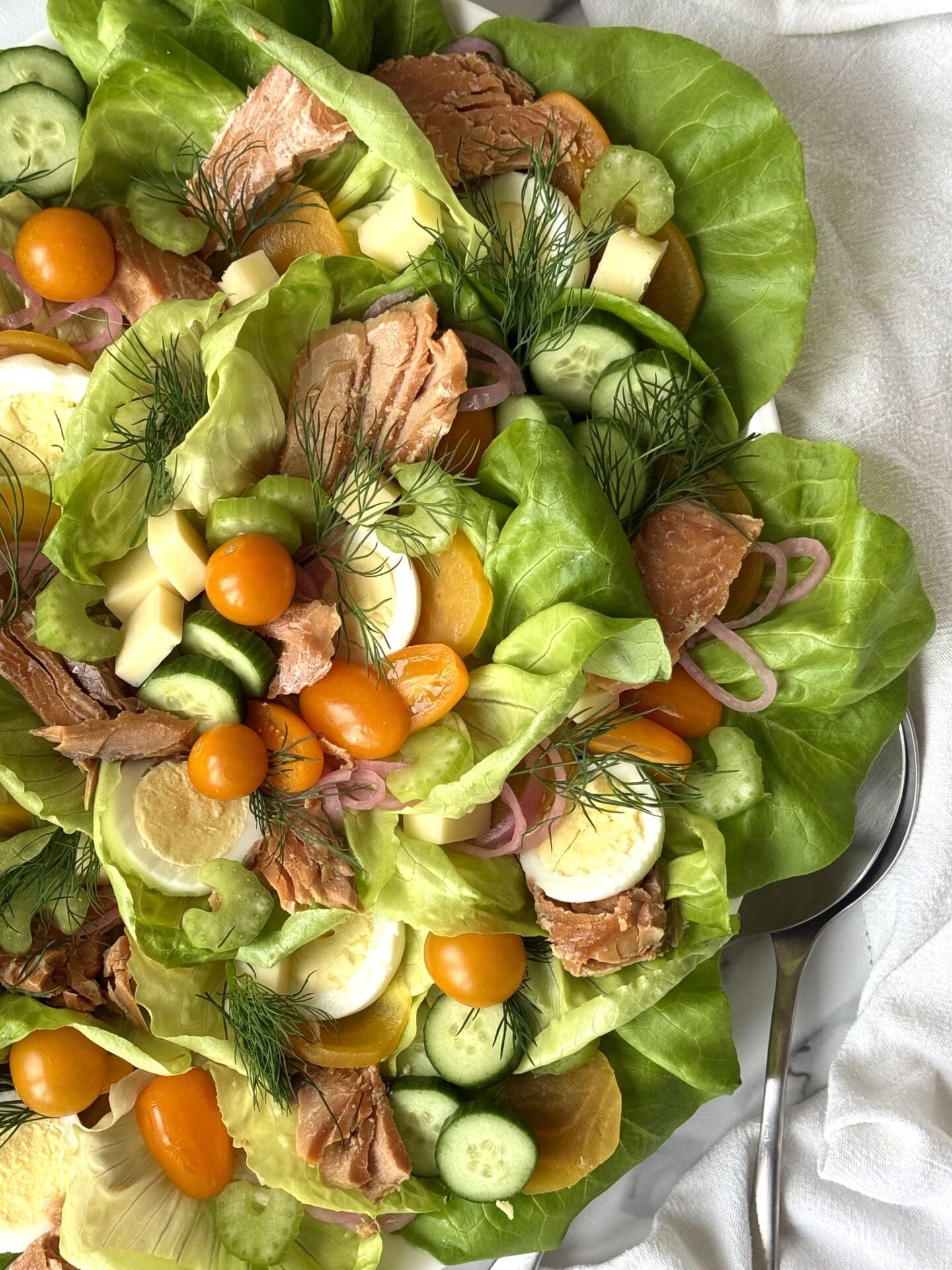 A platter of Irish Pub Salad with Hot Smoked Salmon fills most of the image, surrounded by crisp white table linens