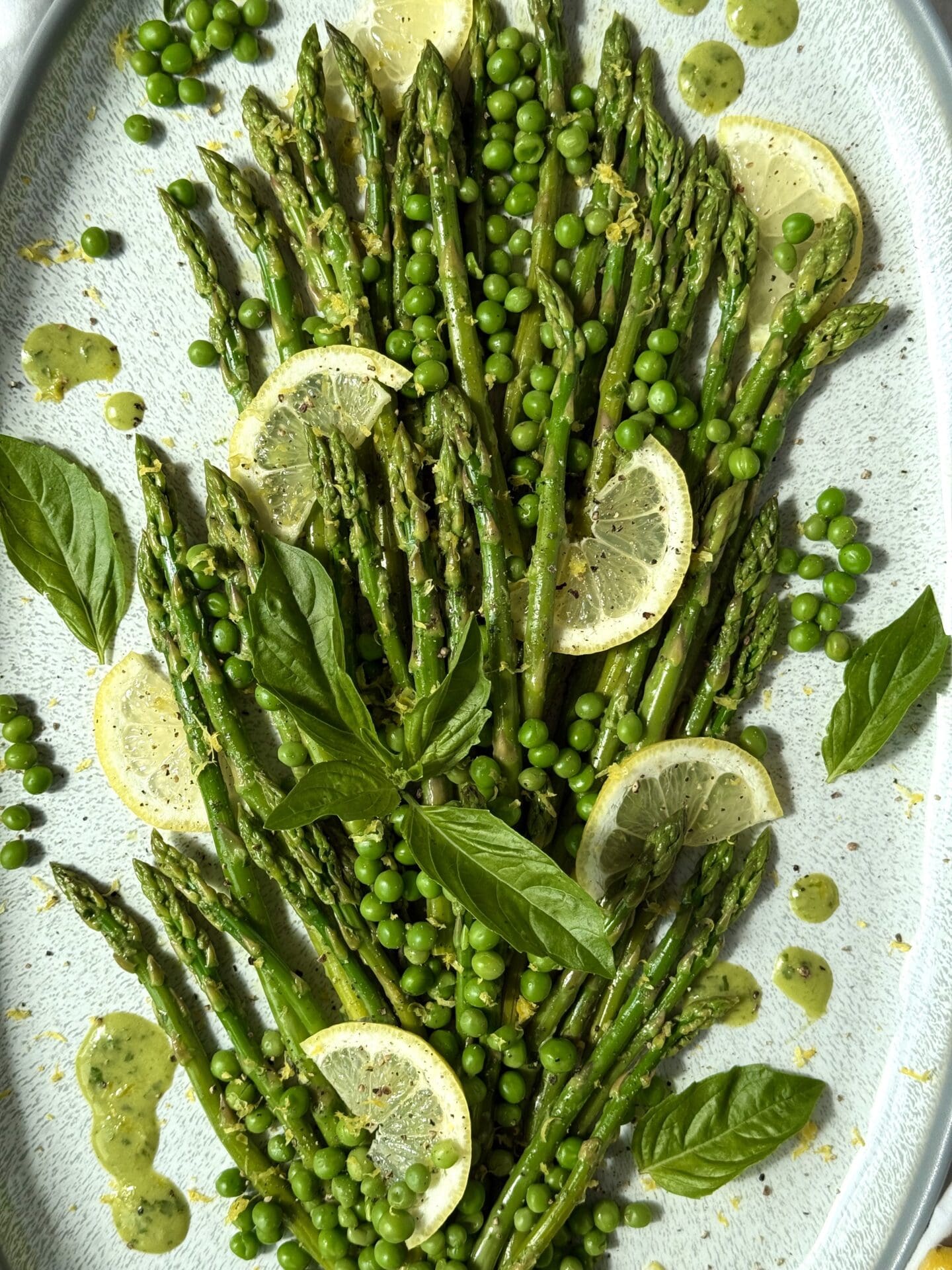 IMG_5384 Lemon Basil Asparagus and Peas side side is seen close up, from above. The image shows the garnishes of lemon slices, fresh basil leaves, lemon zest and black pepper.