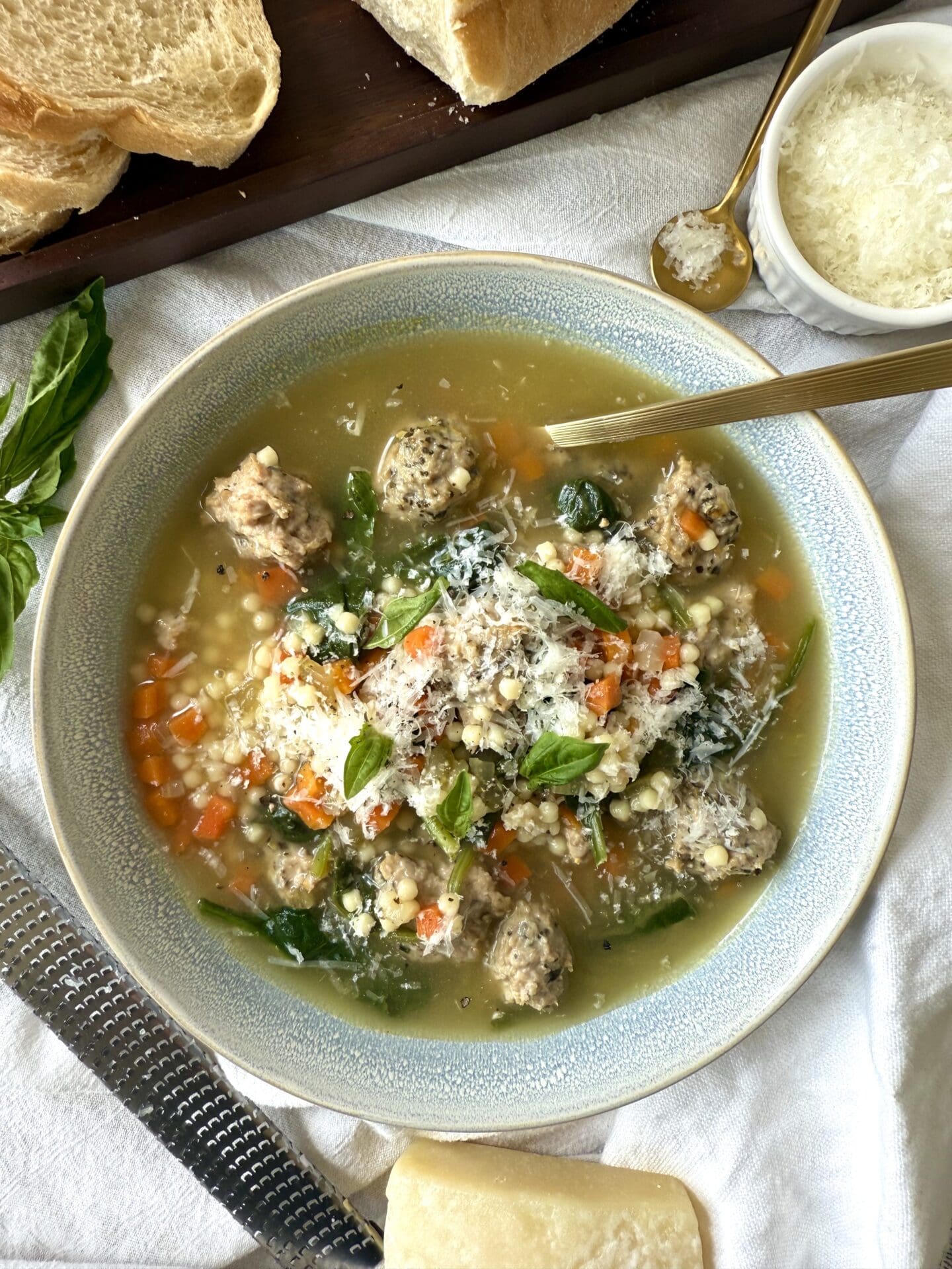 IMG_5716 A bowl of Healthier Italian Wedding Soup is seen from above, laden with turkey meatballs and finely chopped vegetables, and garnished with freshly grated Pecorino Romano cheese.