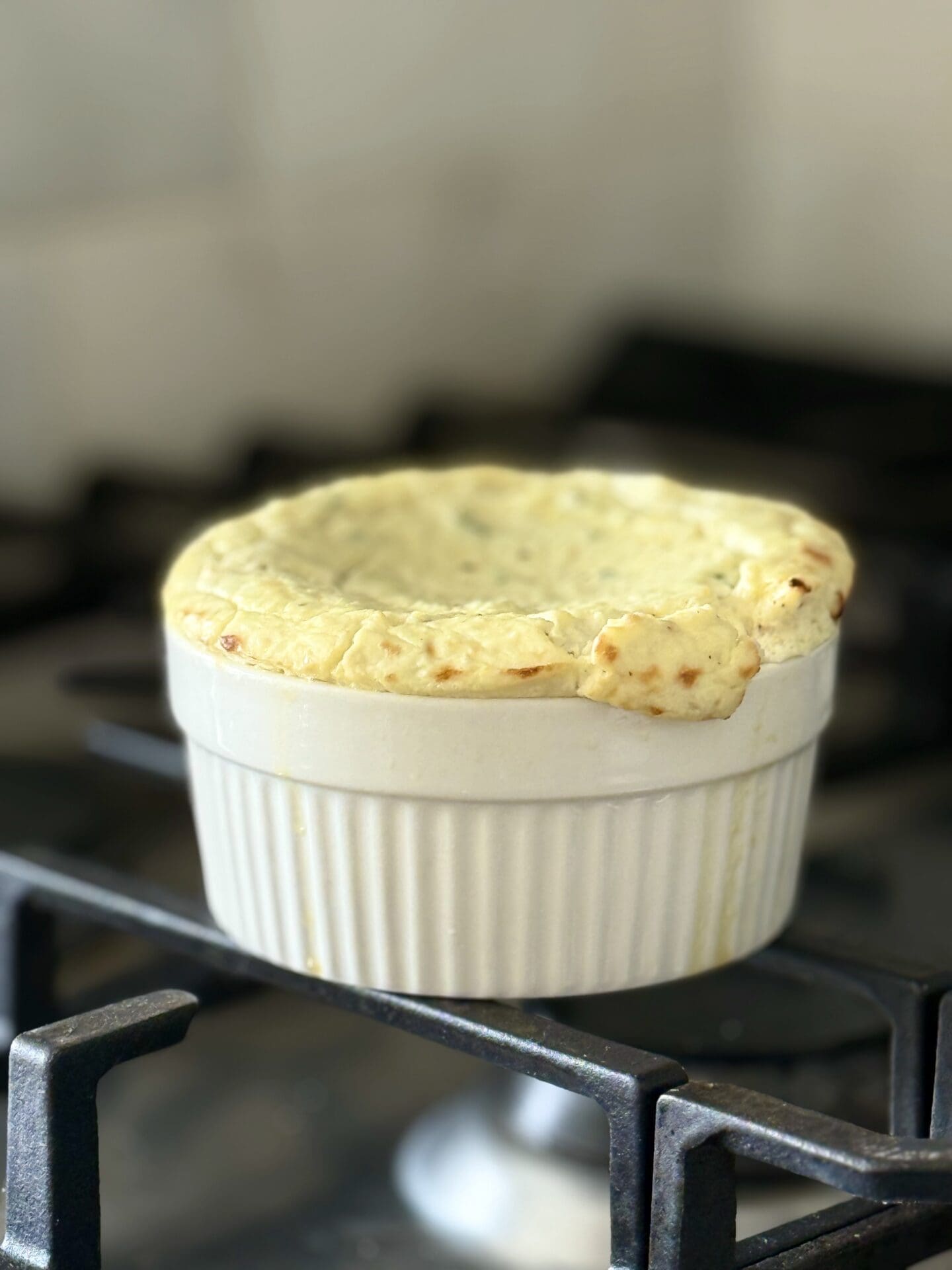 IMG_6936 A baking dish of baked ricotta cools on a stove top. The image shows how the appetizer will rise in the oven like a soufflé, then sink in the centre as it cools.