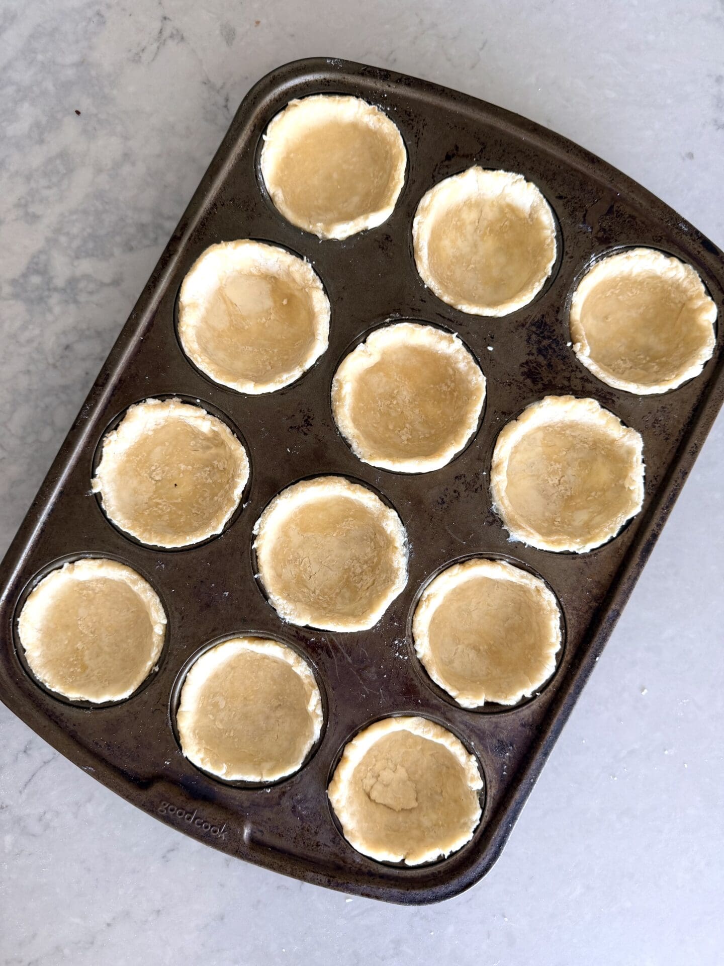 IMG_8422 Rounds of pastry dough are pressed into a regular muffin pan.