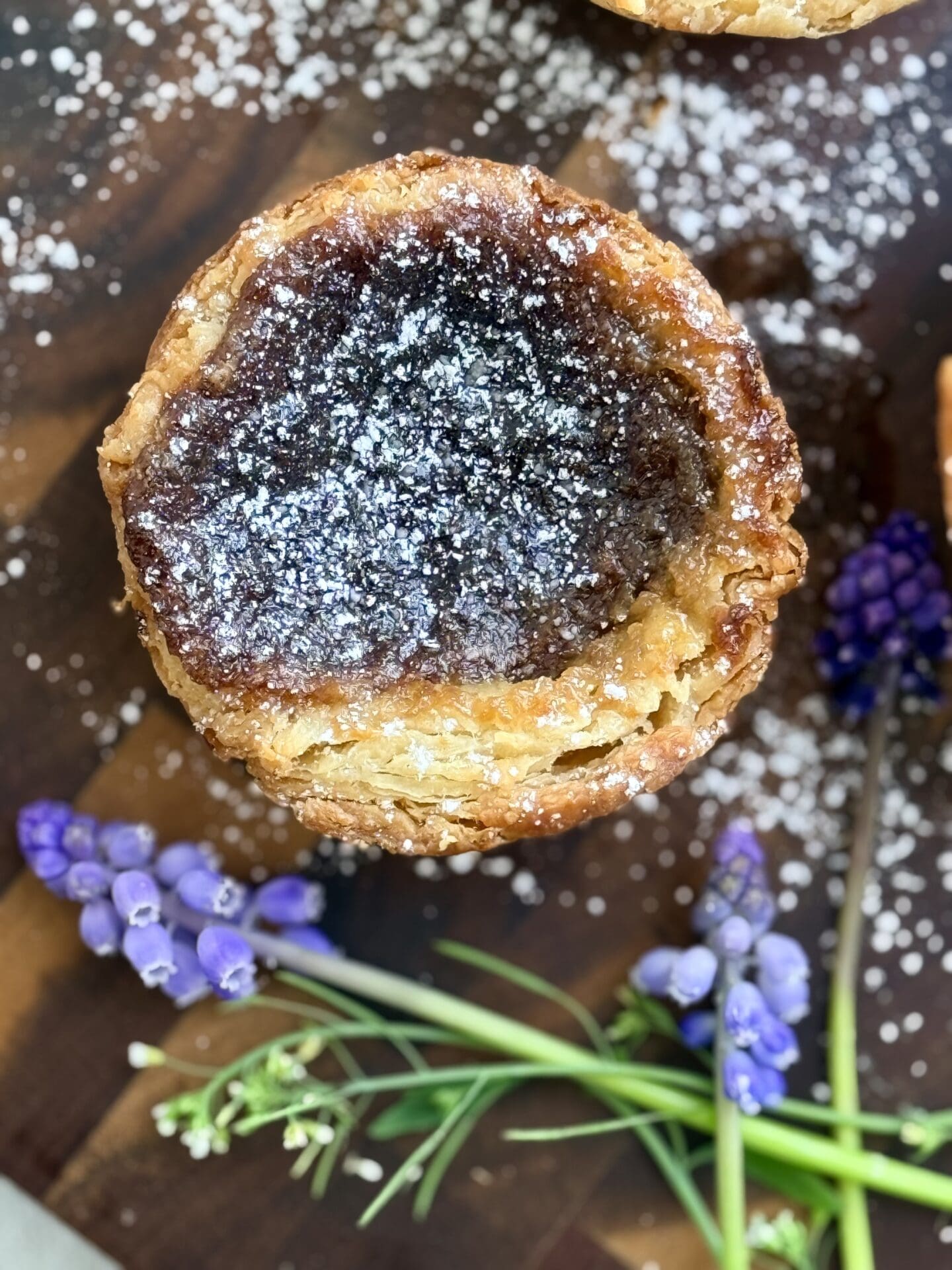 IMG_8450 A single butter tarts sits on a wood board, displaying its flaky, golden crust.
