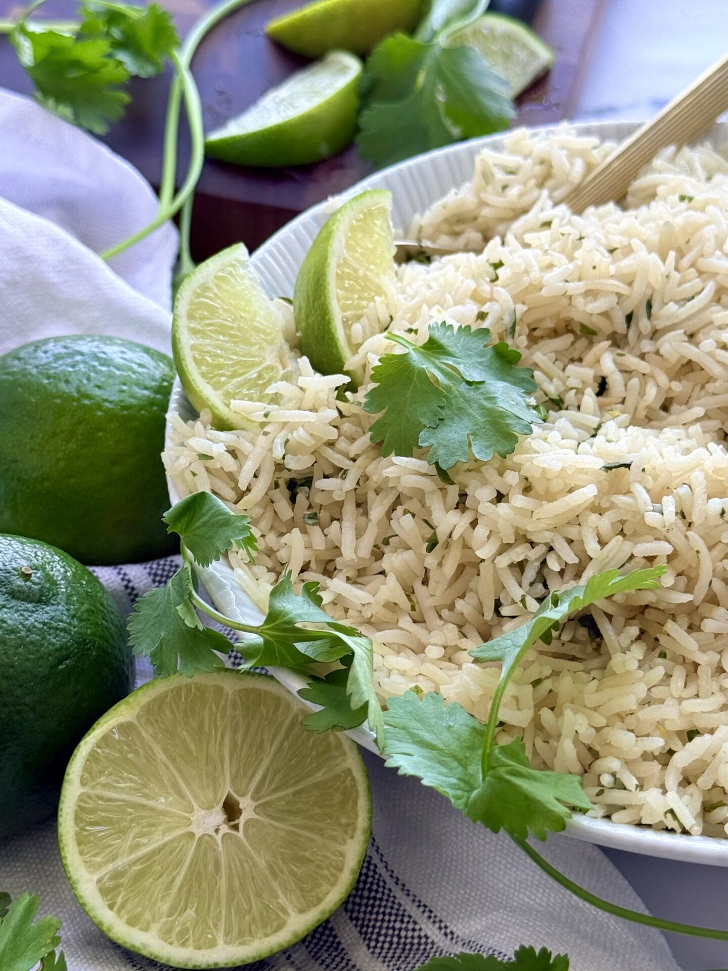 IMG_8971 A bowl of cilantro lime rice slides into the frame from the right, giving the viewer a close look at the seasoned rice. Cilantro leaves and fresh lime slices garnish the bowl.