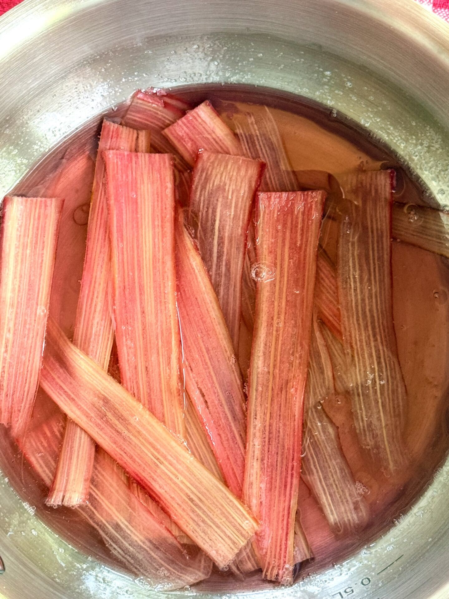 Strips of rhubarb soak in simple syrup before being made into candied rhubarb ribbons.