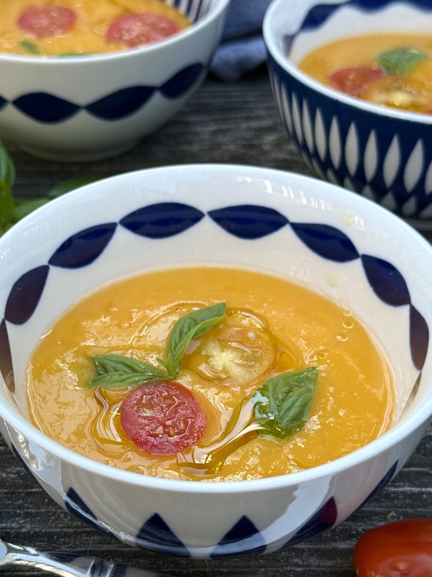IMG_9807 A collection of blue and white bowls are filled with vibrant Yellow Tomato Gazpacho and garnished with olive oil, tomatoes and basil.