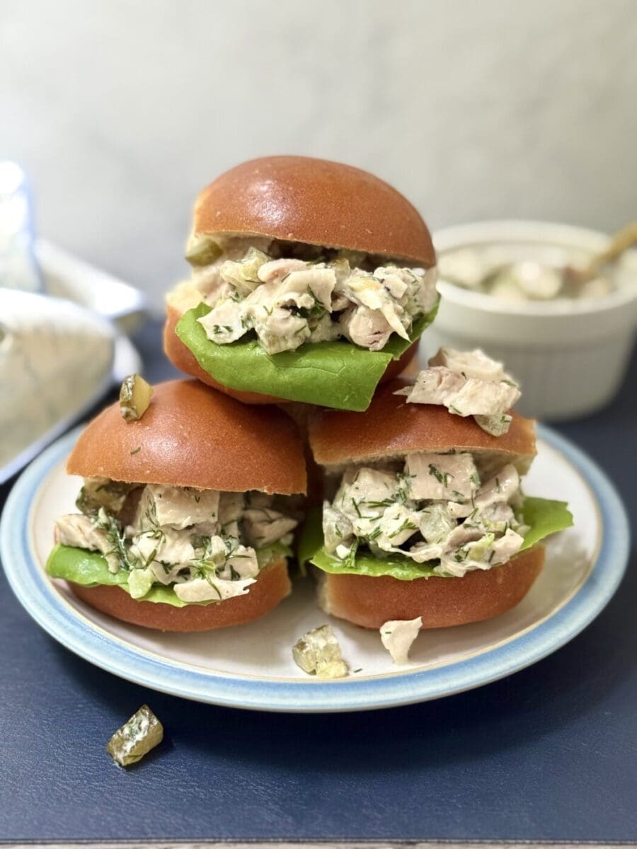 Three golden buns are seen overflowing with Greek Yogurt Dill Pickle Chicken salad.