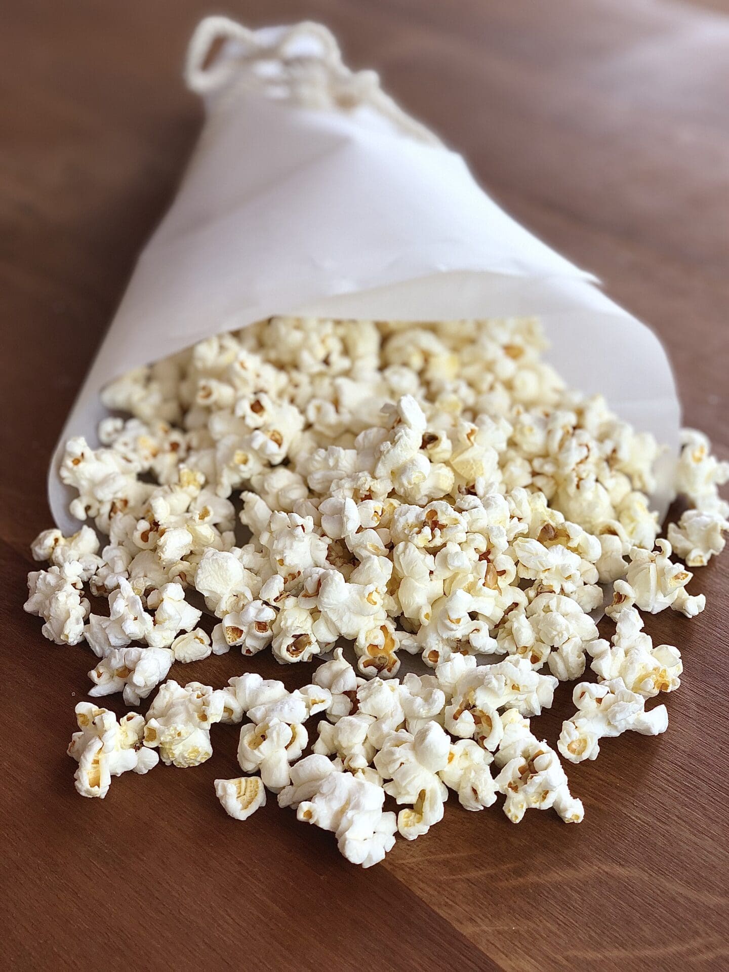 Paper cone of truffle popcorn spilling out onto a wood table