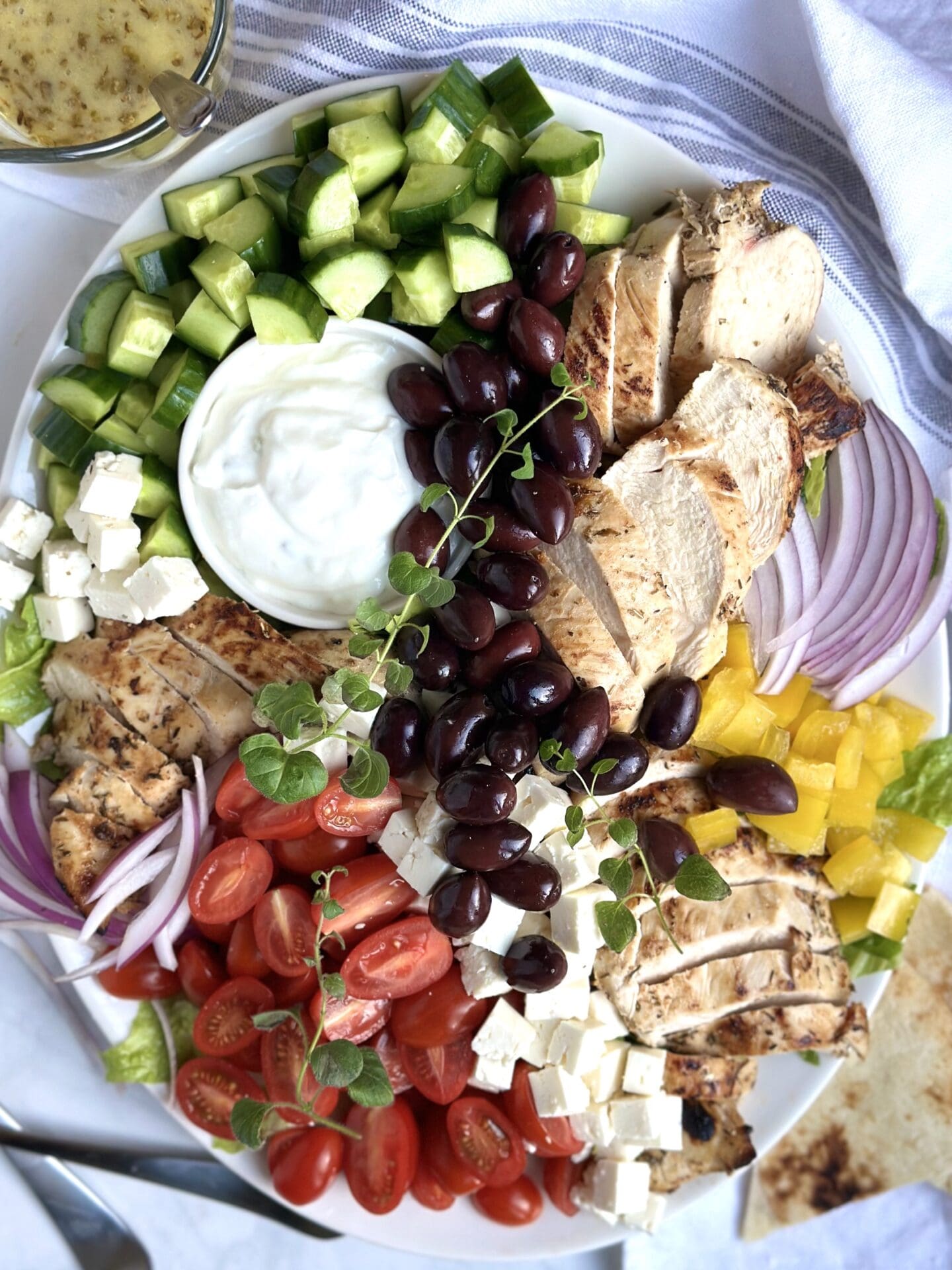 IMG_0441 A large platter of Grilled Chicken Greek Salad is seen from above with generous amounts of tomatoes, cucumber, chicken, feta cheese and olives