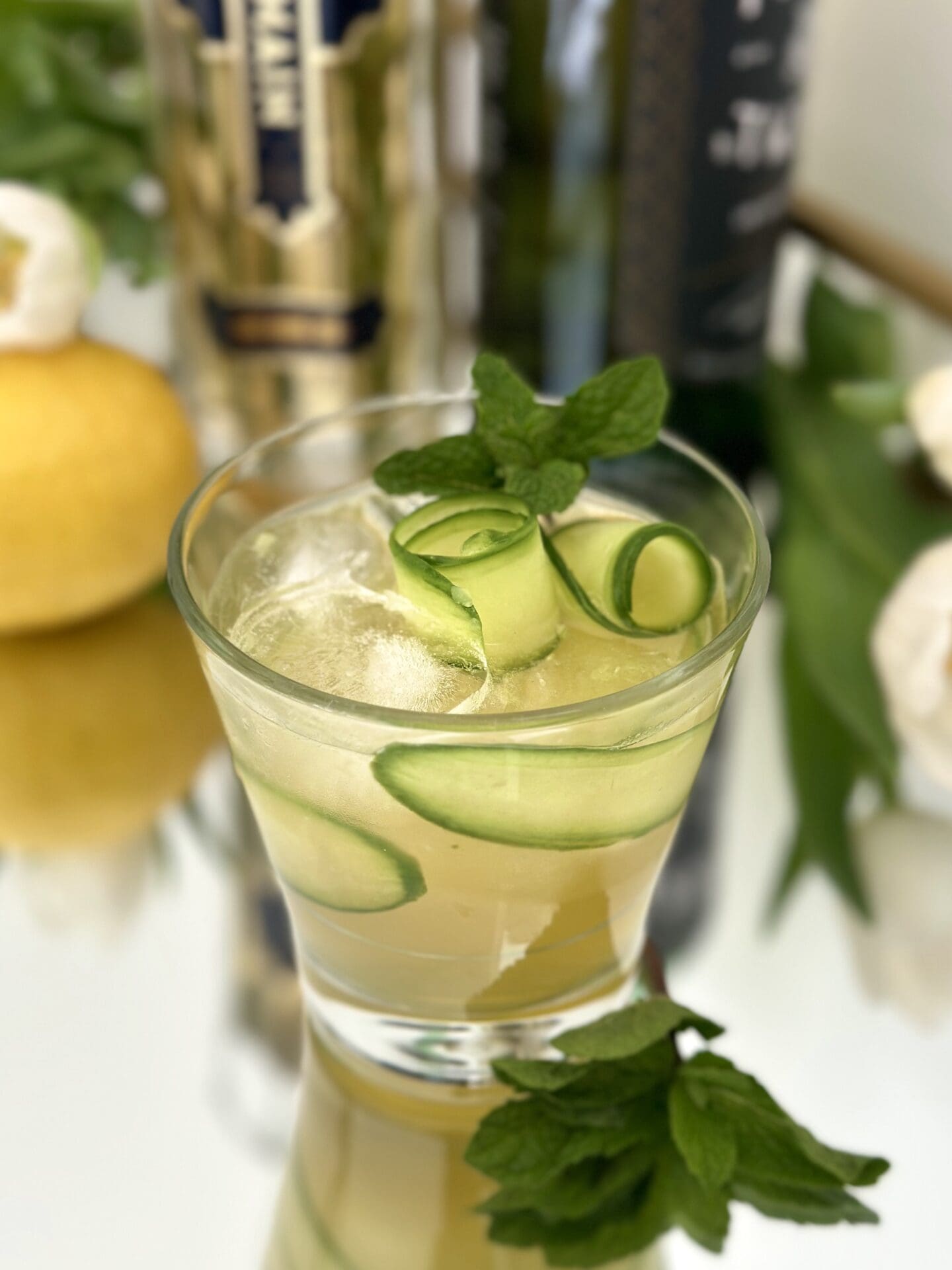 IMG_1335 An Irish Maid Cocktail garnished with cucumber curls and fresh mint sits on a sparkling bar surrounded by bottles of Irish Whiskey and St Germain Elderflower Liqueur