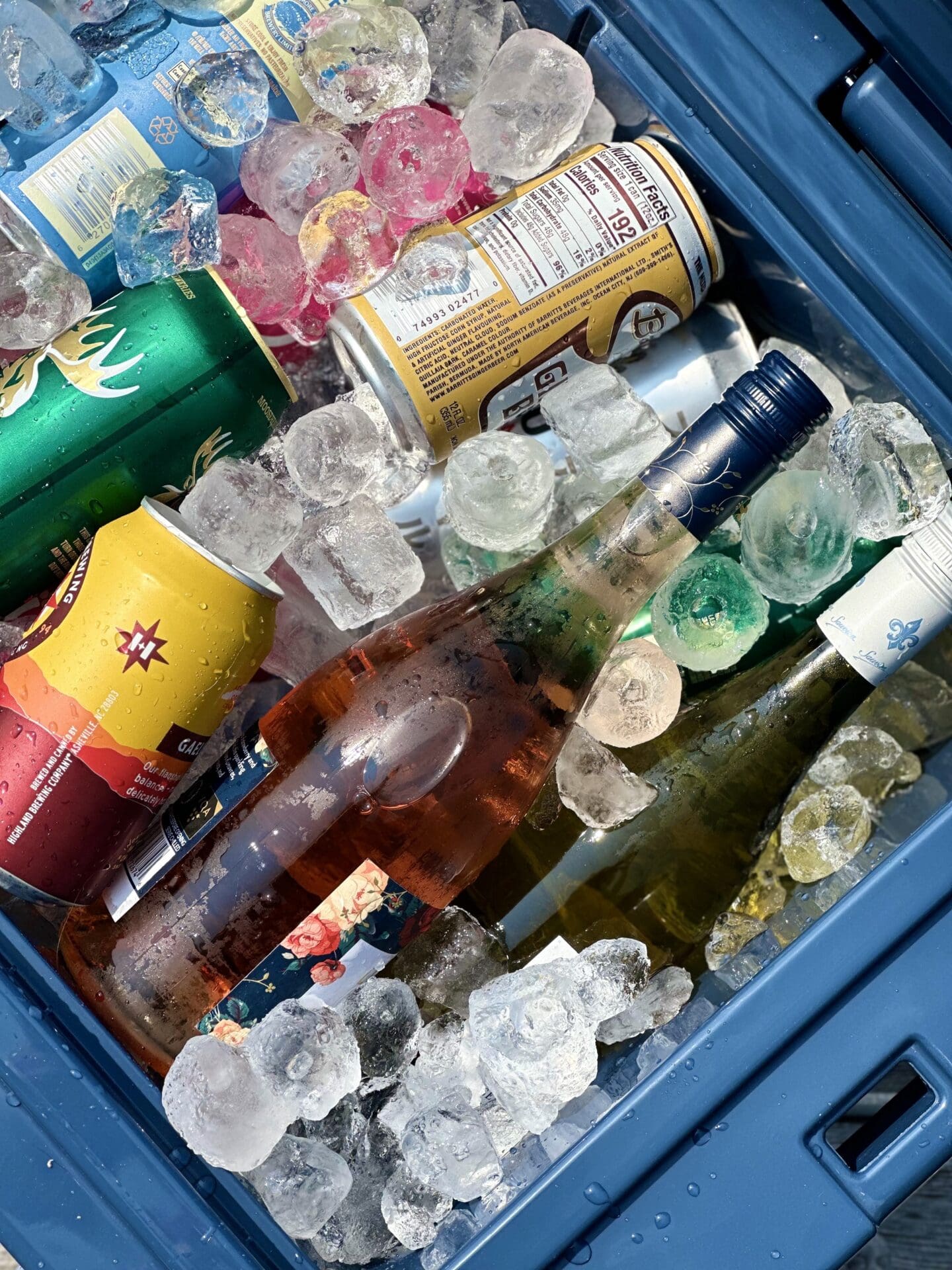 IMG_2671 An open dark blue cooler filled with ice, drink cans and wine bottles is seen from above