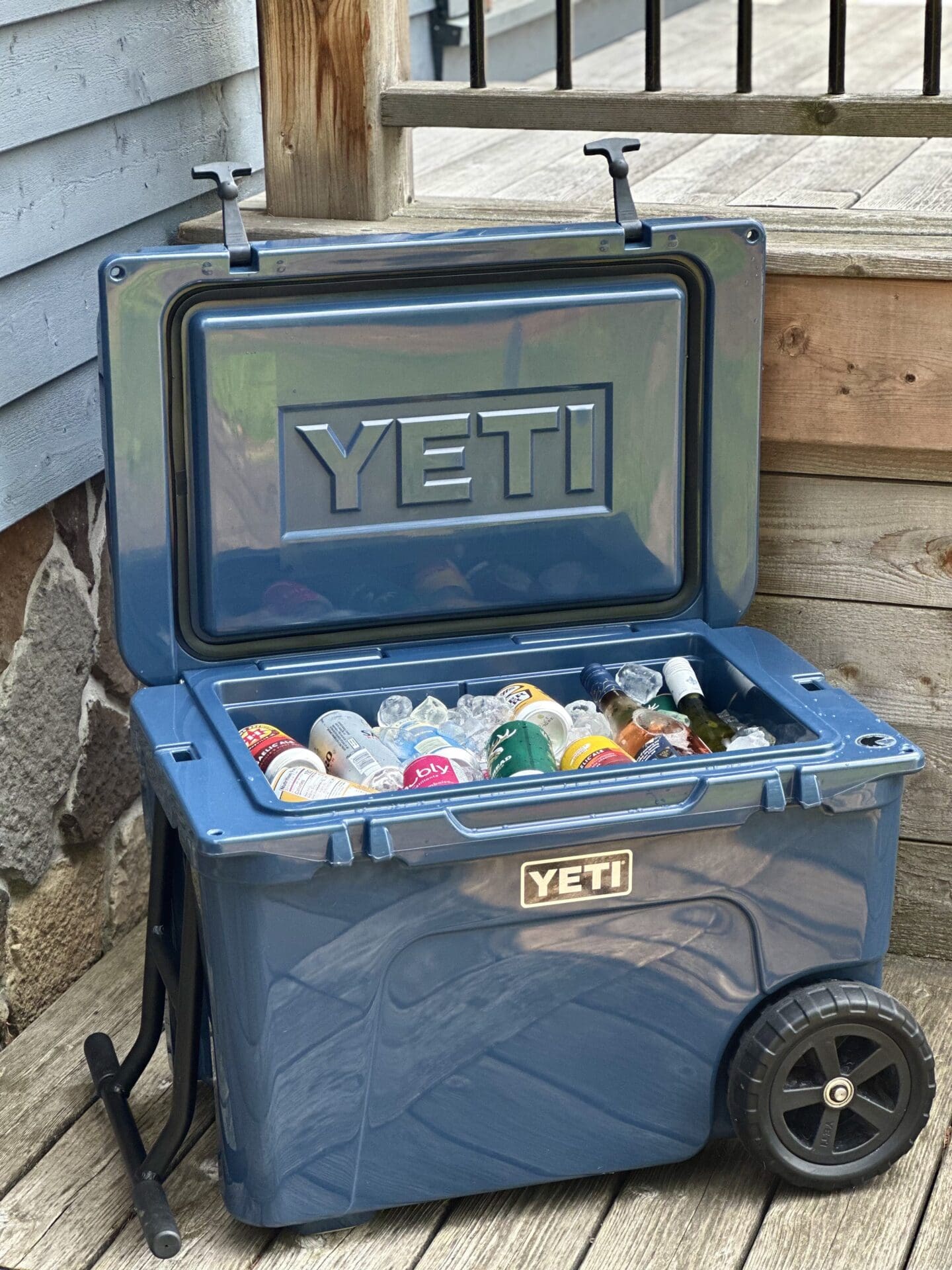 IMG_2685 A dark blue Yeti cooler filled with ice and drinks sits open on a sunny deck