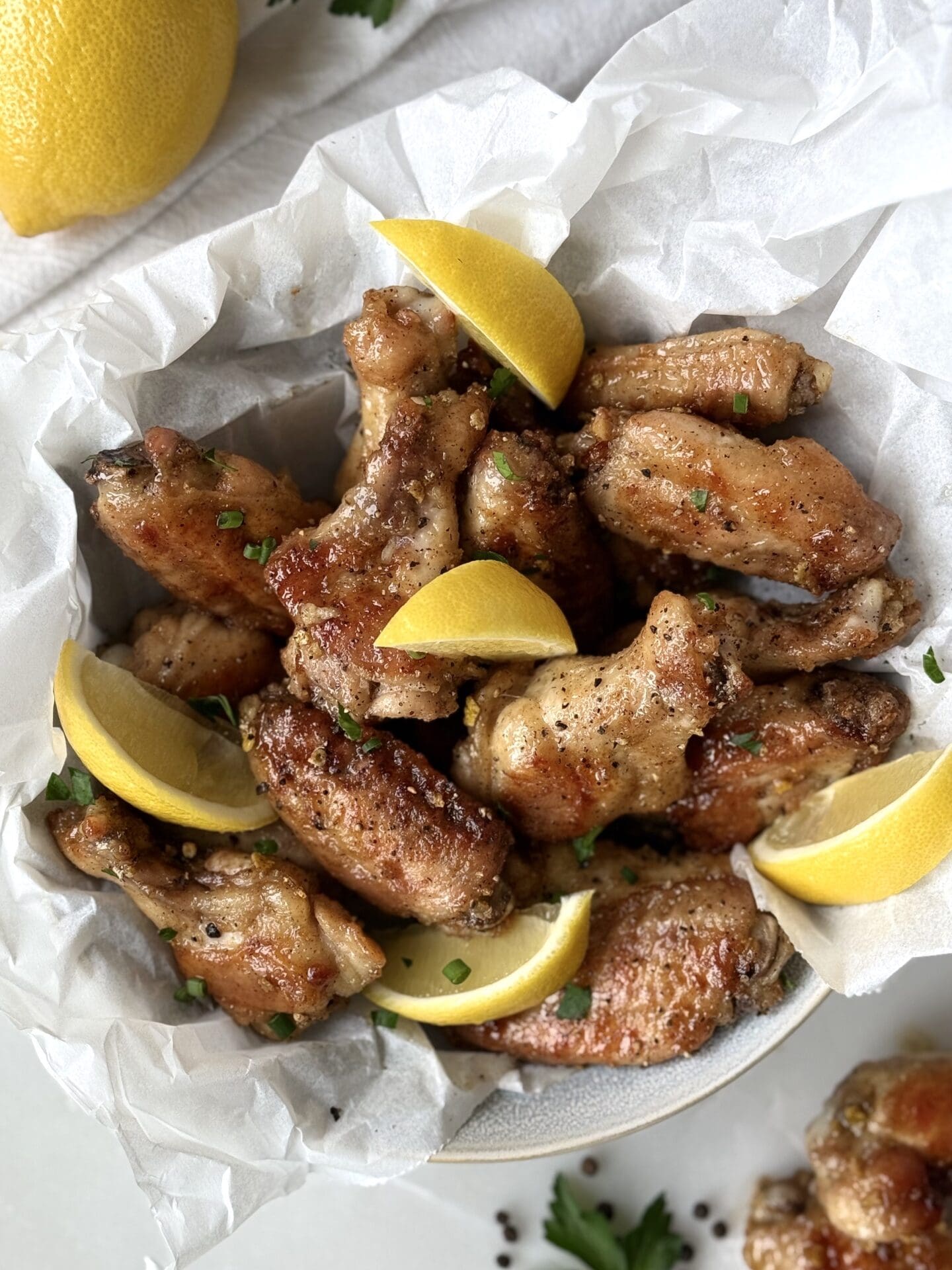 IMG_4267 A bowl of golden Lemon Pepper Chicken Wings is seen from above, garnished with lemon wedges, parsley and chives