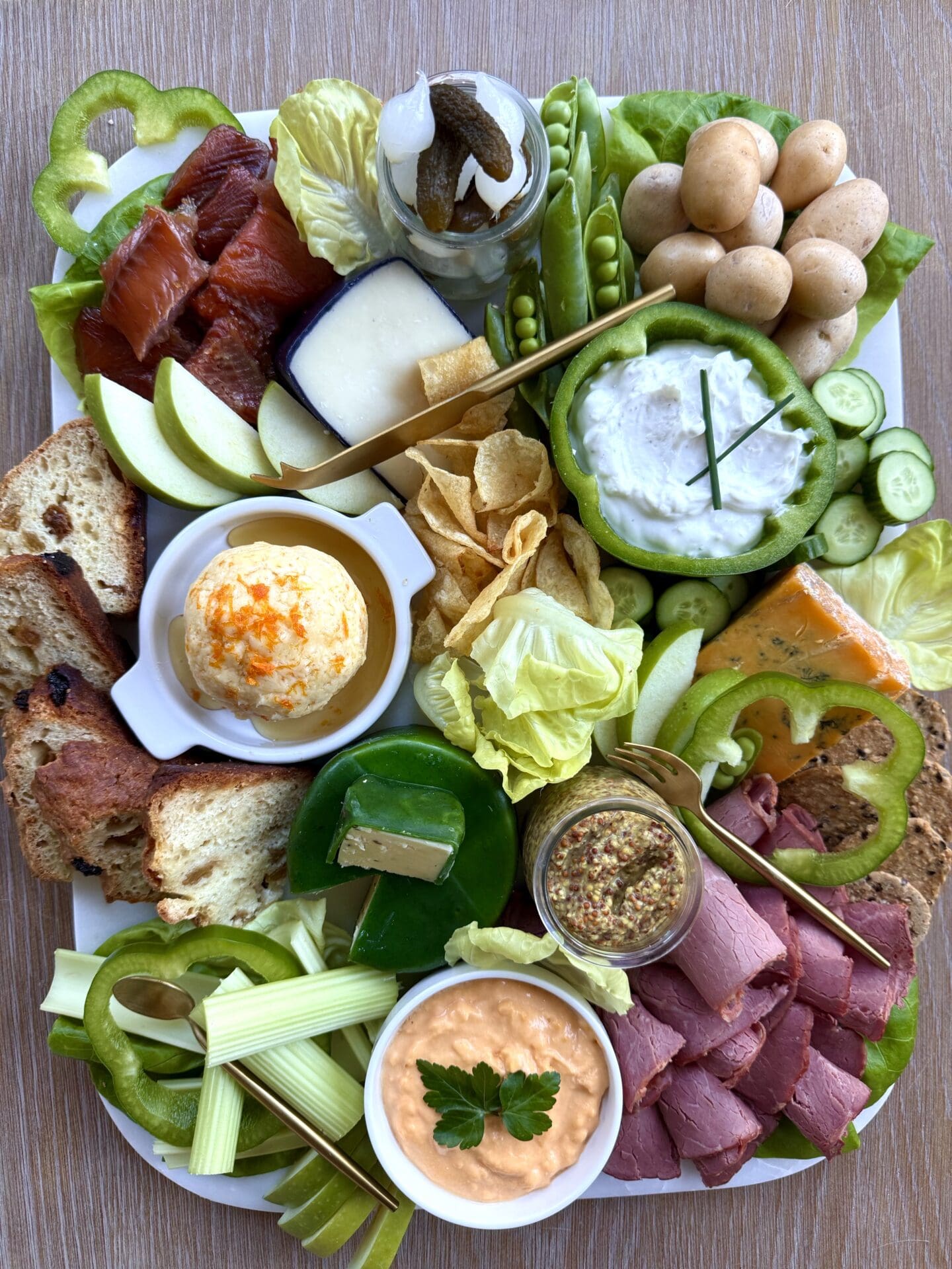A lush St Patrick's Day Charcuterie board is seen from above. The board features cheeses, meats, vegetables and fruits in the colours of the Irish flag.