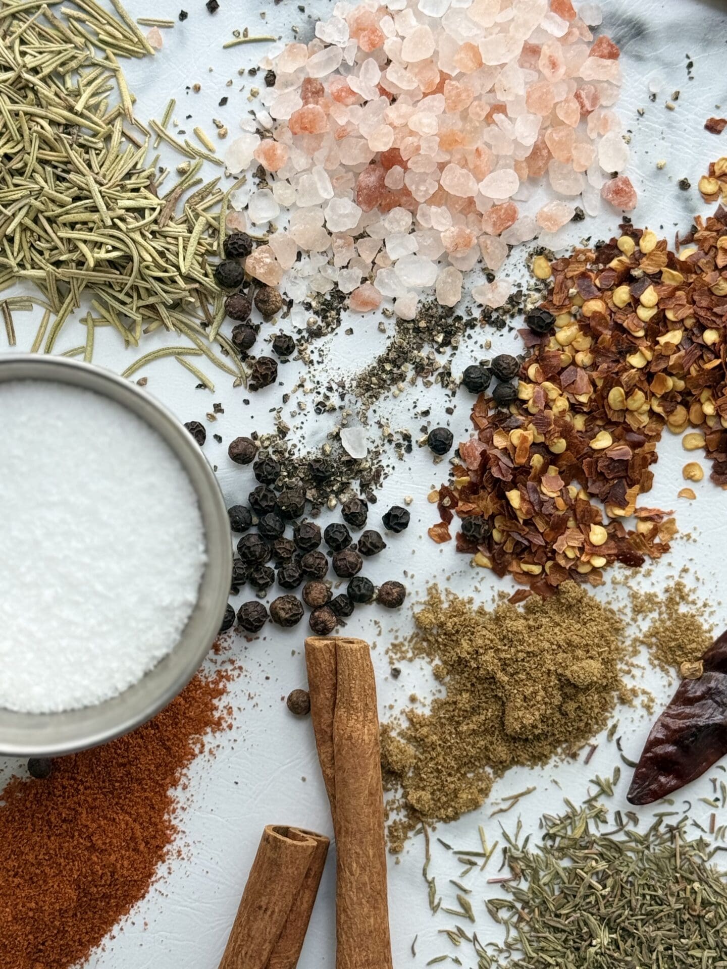 A selection of dried herbs and spices is spilled on a countertop