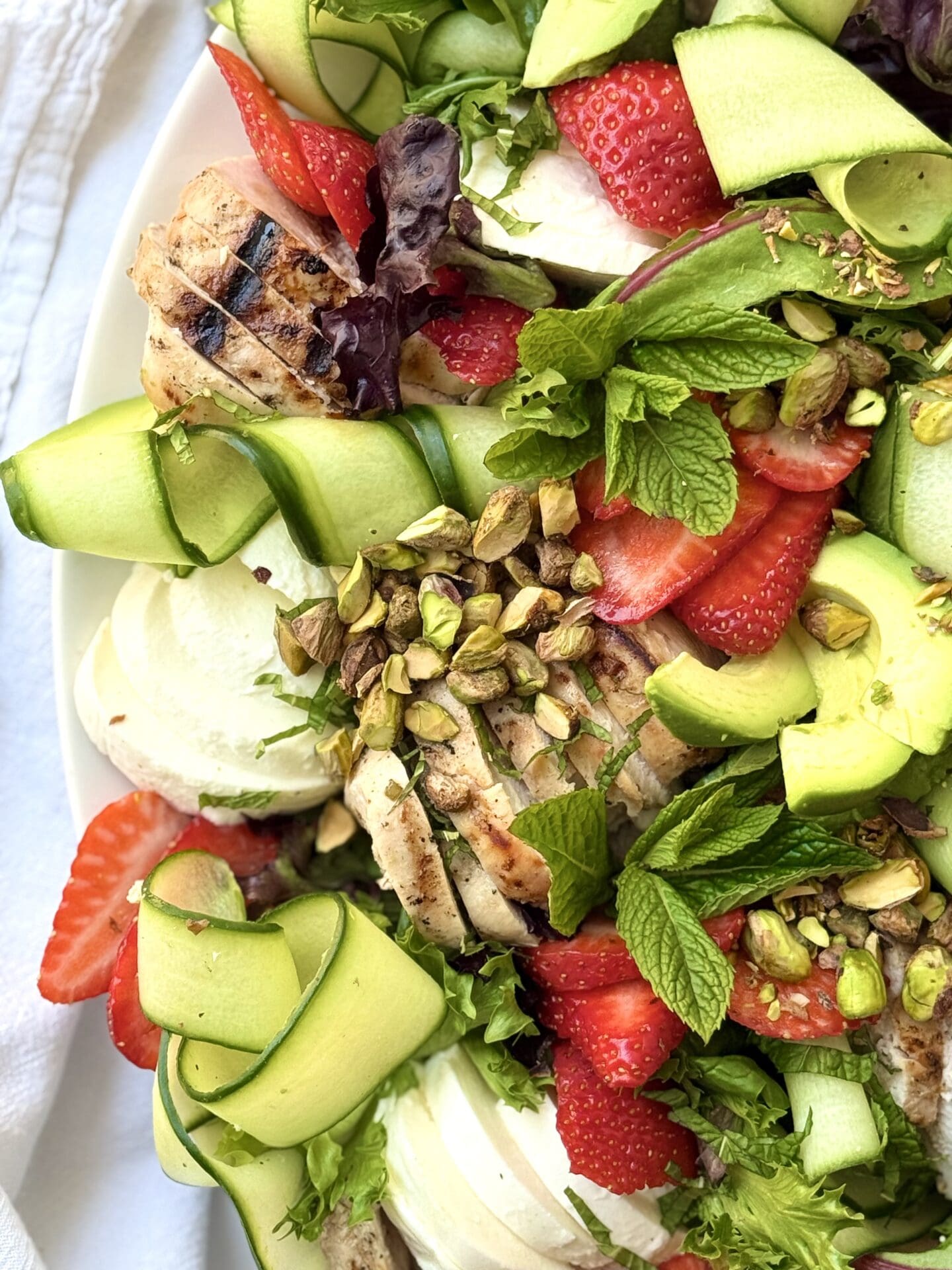 IMG_8880 A close up photo of Strawberry Cucumber Salad with Grilled Lemon Chicken shows off its vibrant berries and crisp cucumbers curls.