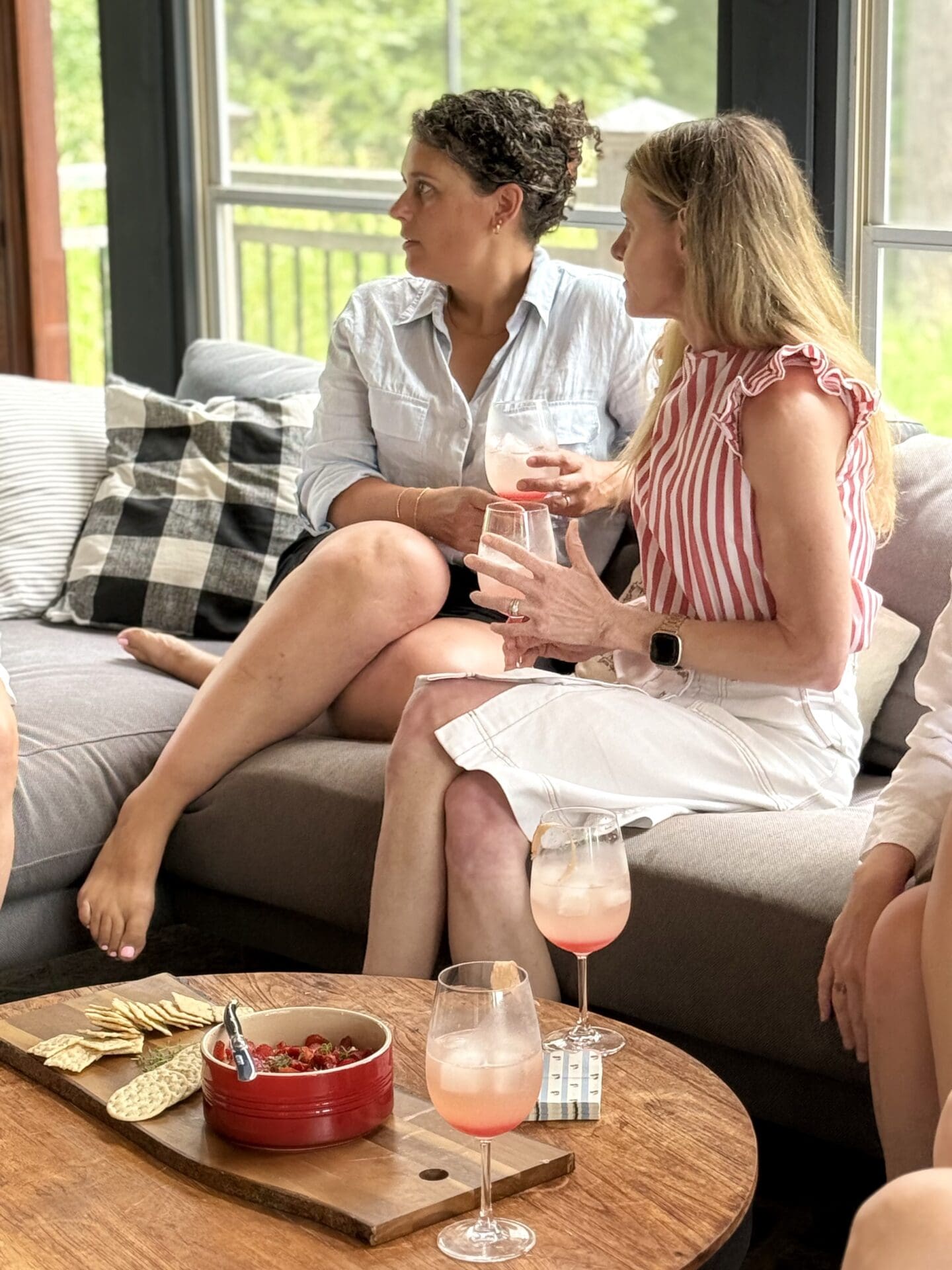IMG_9520 Two women sit on a screened in porch, deep in conversation while enjoying a cocktail and appetizer.