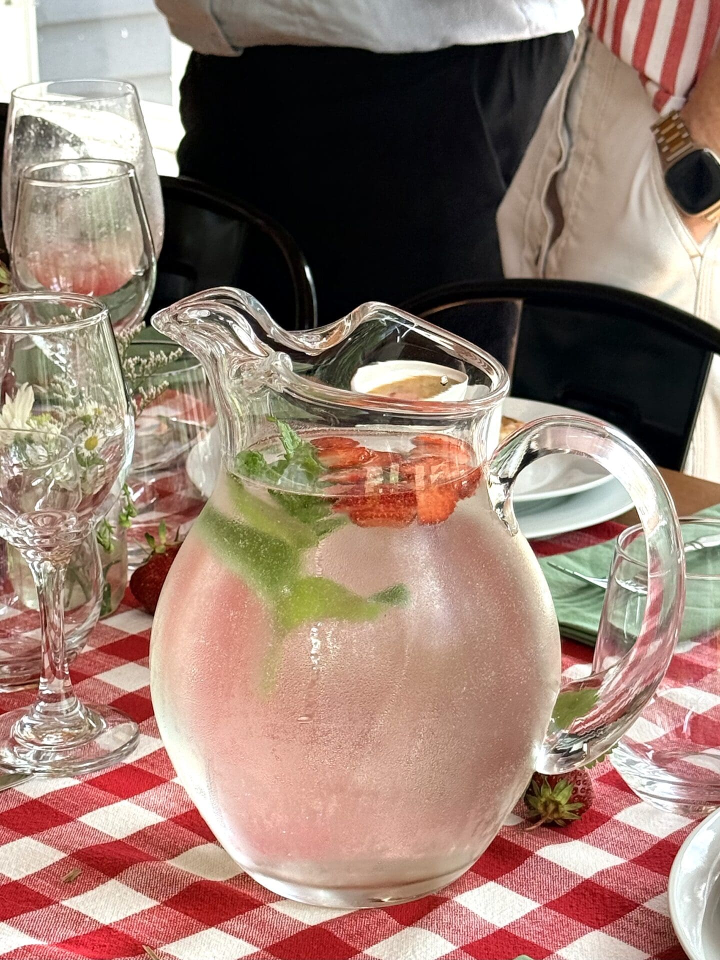 IMG_9528 A glass pitcher filled with strawberry and mint ice water rests on a table set for lunch.